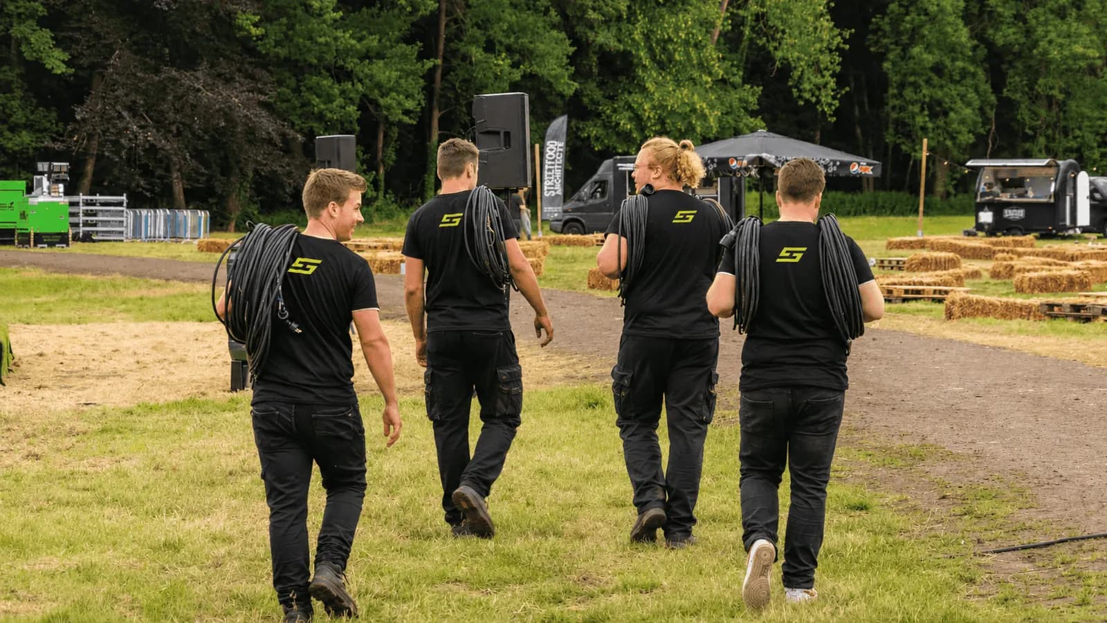 Team van Stroomhuren.be draagt kabels over een festivalterrein